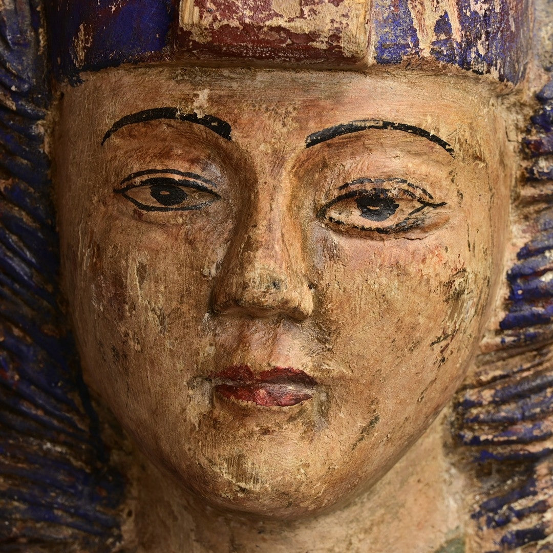 Close-up of a wooden sculpture with detailed facial features and blue and gold background