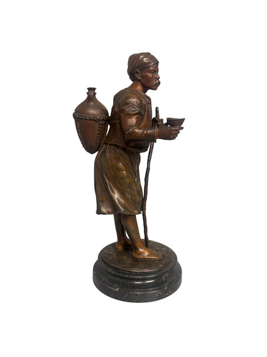 Late 19th-century bronzed metal figure of an Arabian water carrier on a black marble base.
