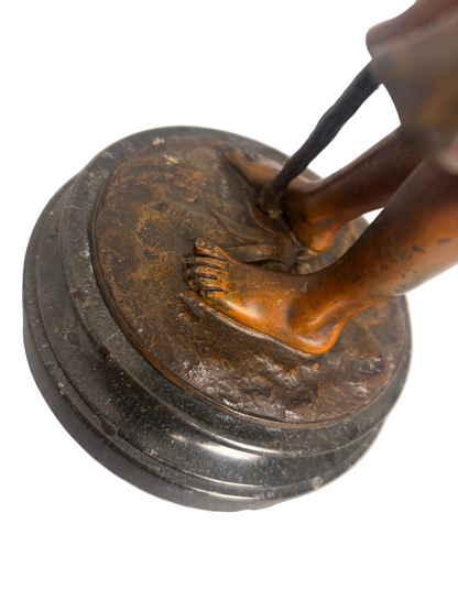 Bronze statue of a foot on a circular base with a white background