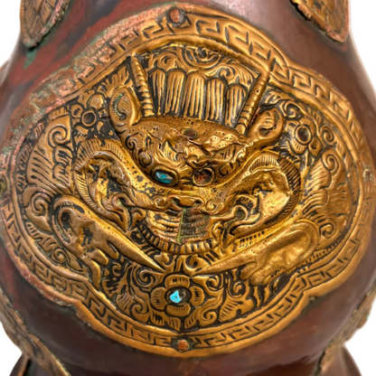 Copper and gilt-brass repoussé Sino-Tibetan style ewer with turquoise inlay and dragon mask medallion, domed lid and spout.