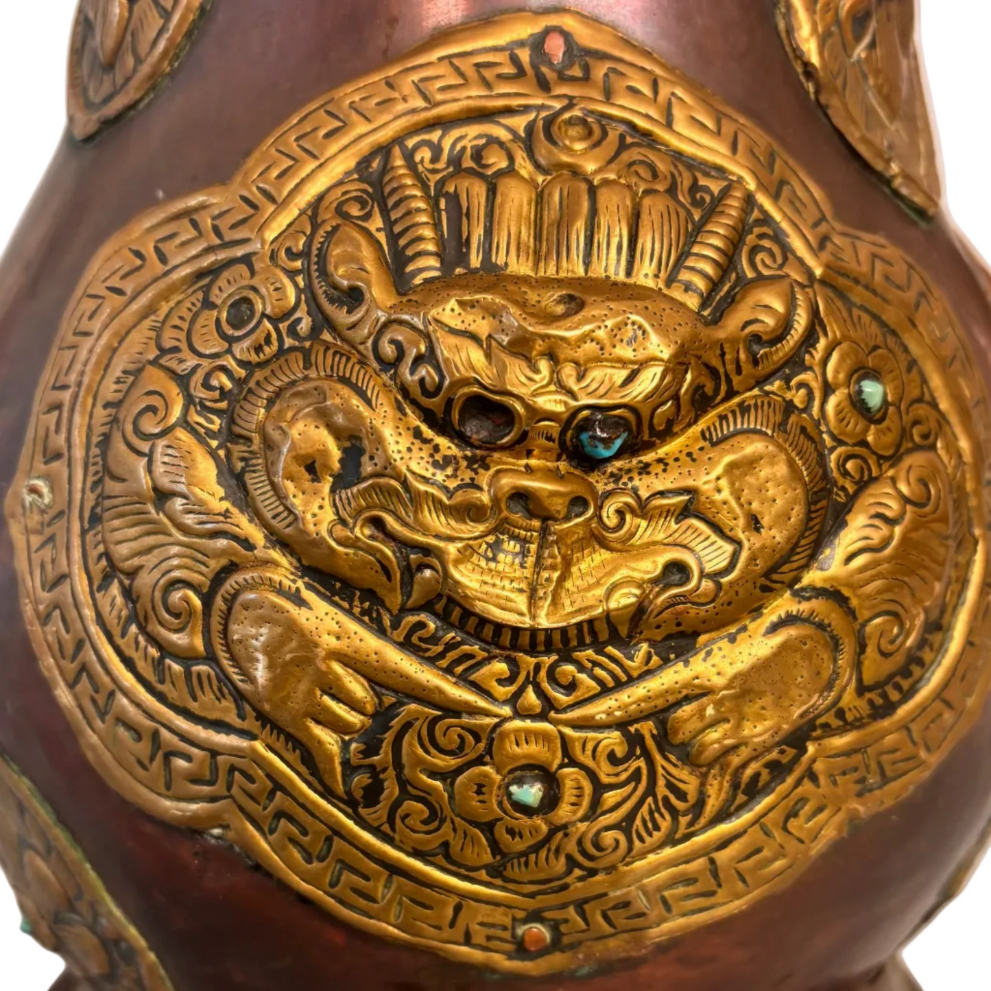 Copper and gilt-brass repoussé Sino-Tibetan style ewer with turquoise inlay and dragon mask medallion, domed lid and spout.
