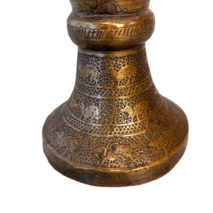Detail of Persian brass vase showing engraved animals on base.