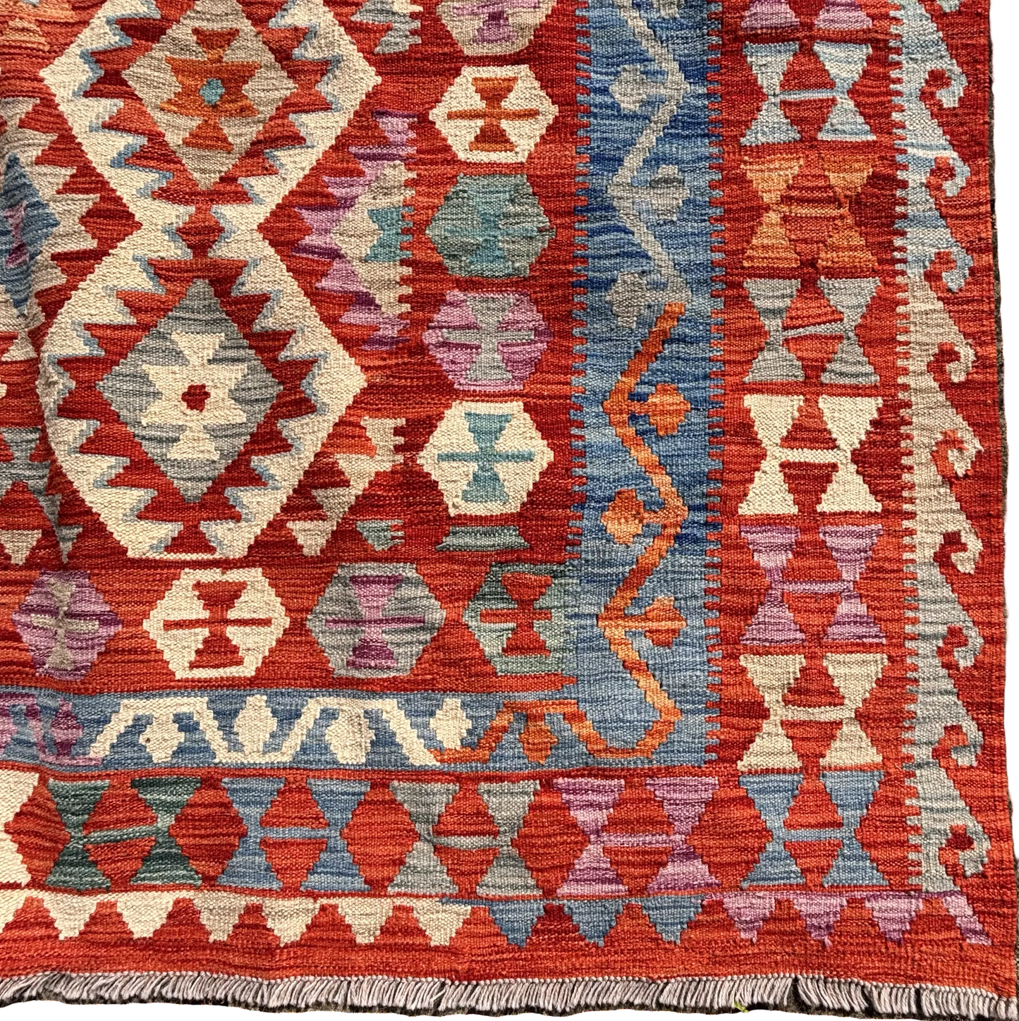 Close up of geometric diamond motifs in red, blue and ivory wool flatweave