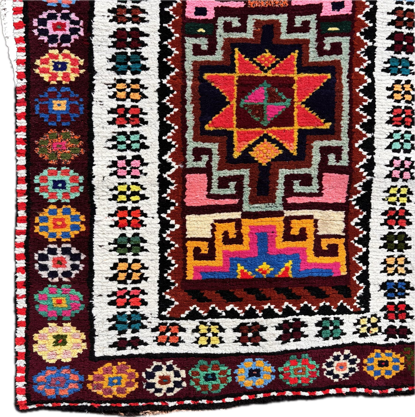 Close up of central star medallion in vivid pink and turquoise wool