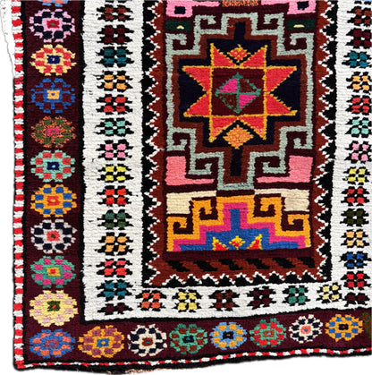 Close up of central star medallion in vivid pink and turquoise wool