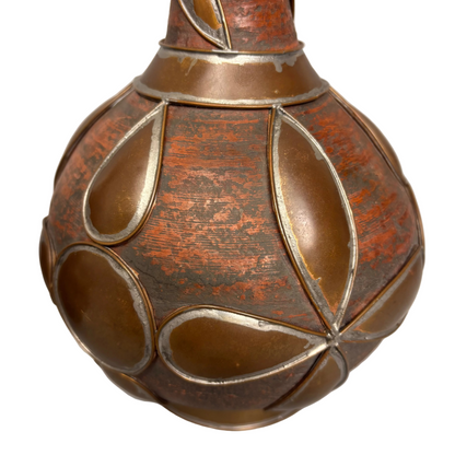 Close-up copper petal motif over red earthenware surface