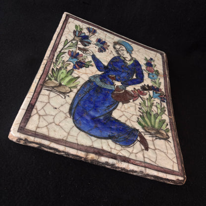 Angled view of Persian Qajar hand-painted ceramic tile